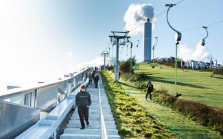 People skiing on a pitched green roof and stairs up to the roof